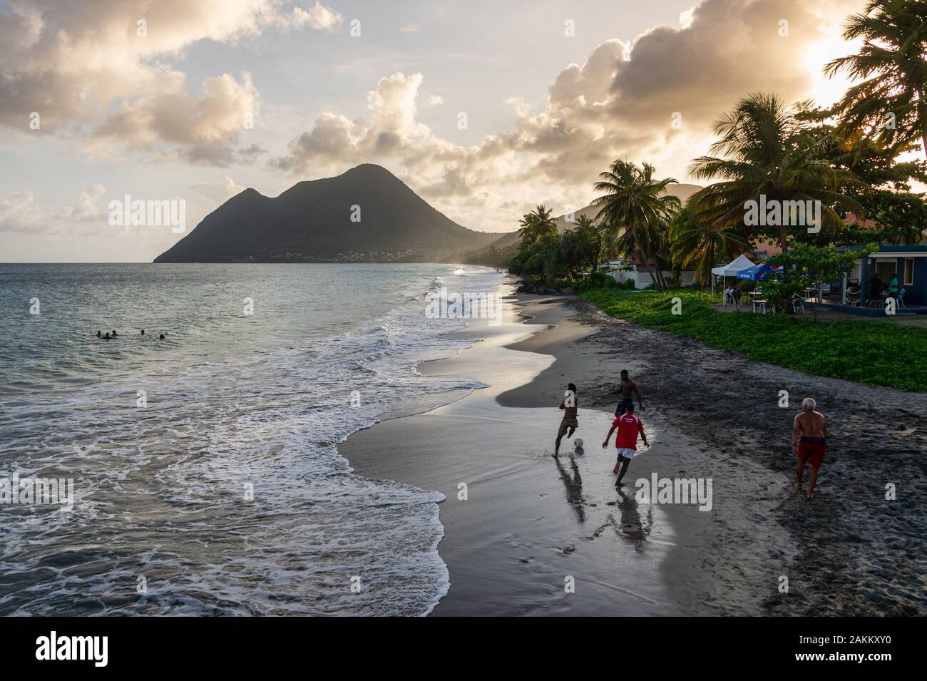 Le Diamant, Martinique, France - 16 August 2019: Le Diamant Beach in Martinique, with men playing with a ball and Sleeping Woman mountain in backgroun Stock Photo