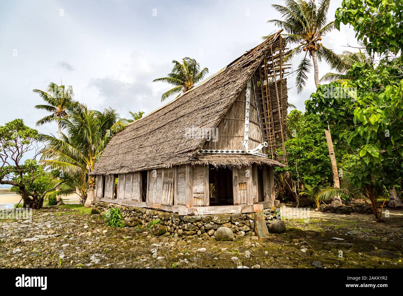 Old traditional thatched yapese men's meeting house faluw or fale, on an elevated limestone platform foundation. Shore of South Pacific ocean. Yap isl Stock Photo