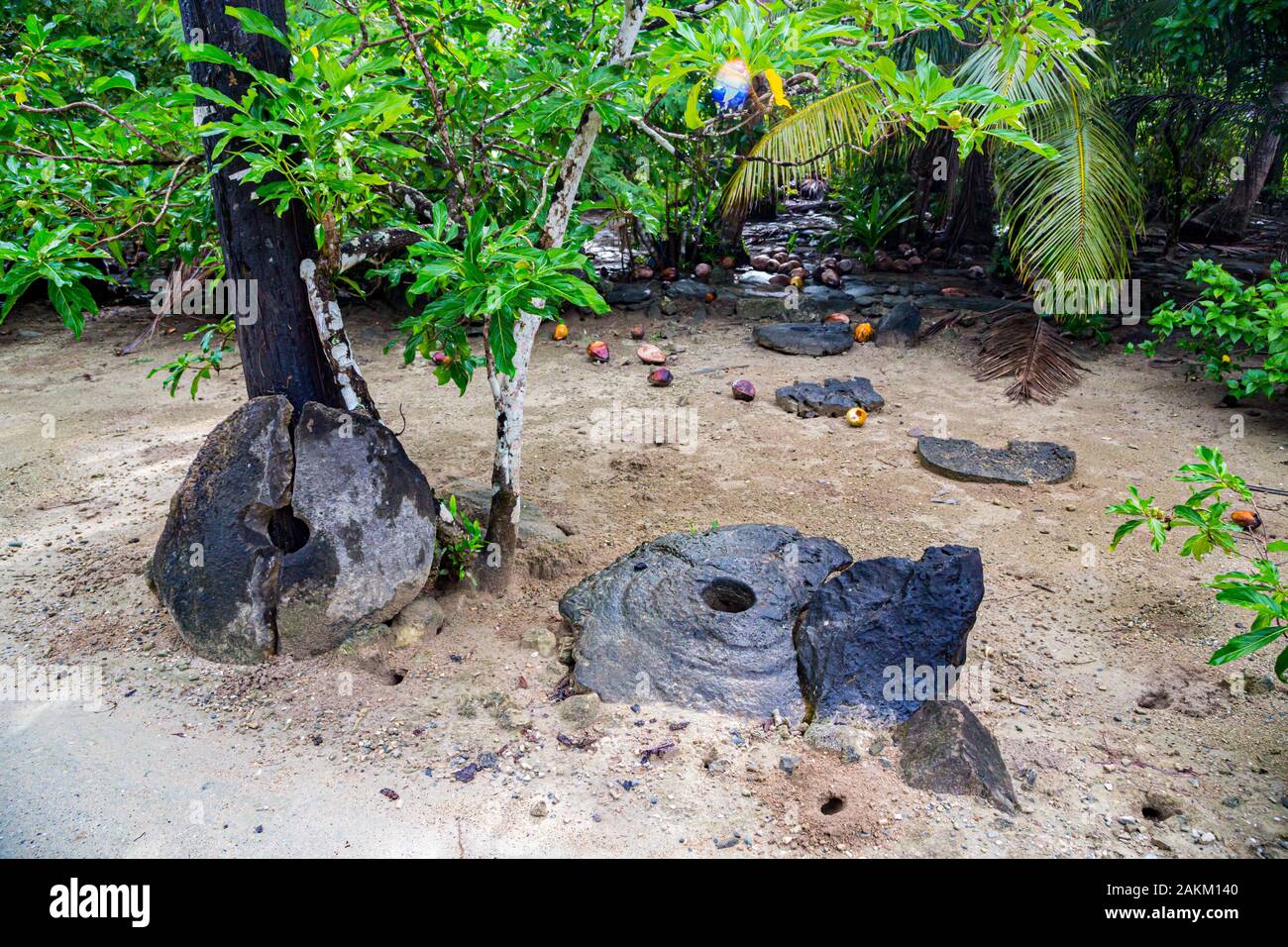 Two giant broken prehistoric megalithic stone coins or money rai, lying in the sand hidden under trees in jungle. Yap island, Federated States of Micr Stock Photo