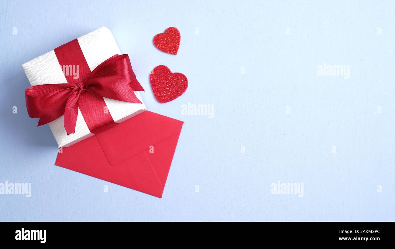 White gift box with red ribbon bow, red paper envelope and hearts on ...