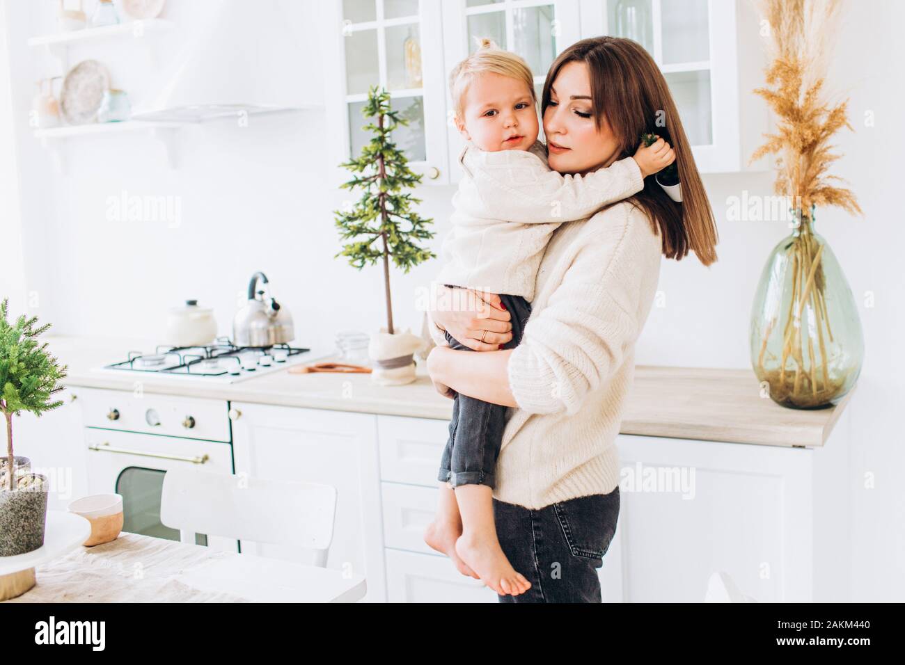 Mother and daughter in a bright kitchen. Homeliness. Joyful baby and his mom.  Stock Photo