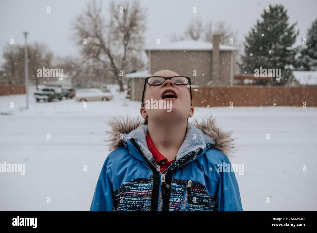 portrait of a girl looking up while it is snowing in front yard Stock Photo