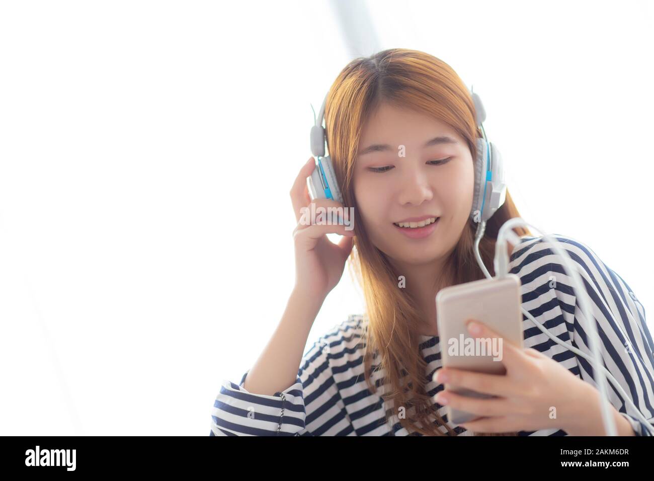 Beautiful asian young woman enjoy listen music with headphone and holding smart mobile phone while sitting in bedroom, relax girl with earphone, leisu Stock Photo