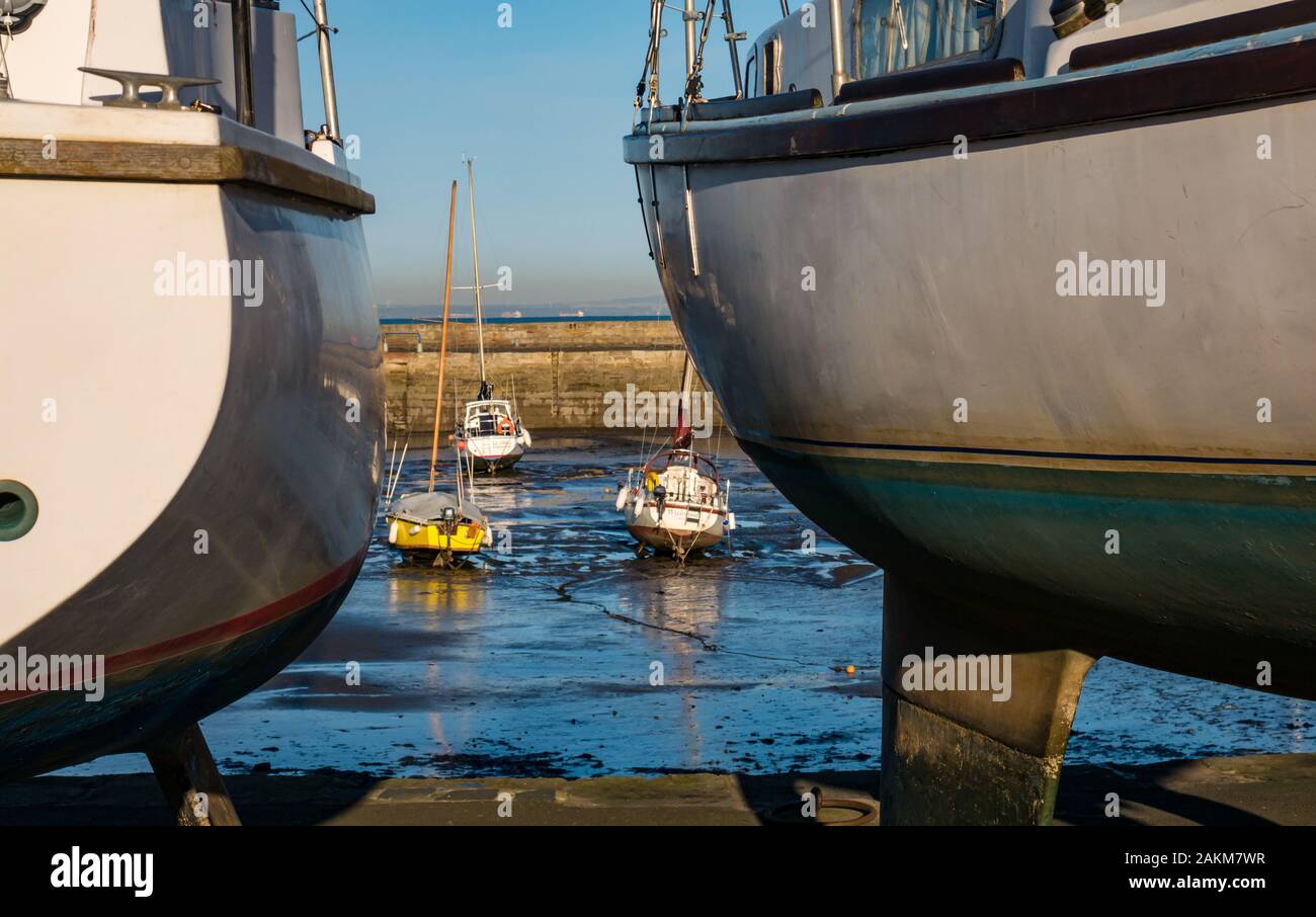 Boat hulls and boats grounded in mud at low tide, Fisherrow Harbour, Musselburgh, Scotland, UK Stock Photo