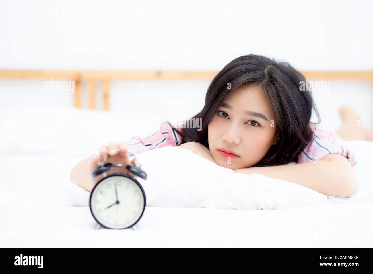 Beautiful asian young woman turn off alarm clock in morning, wake up