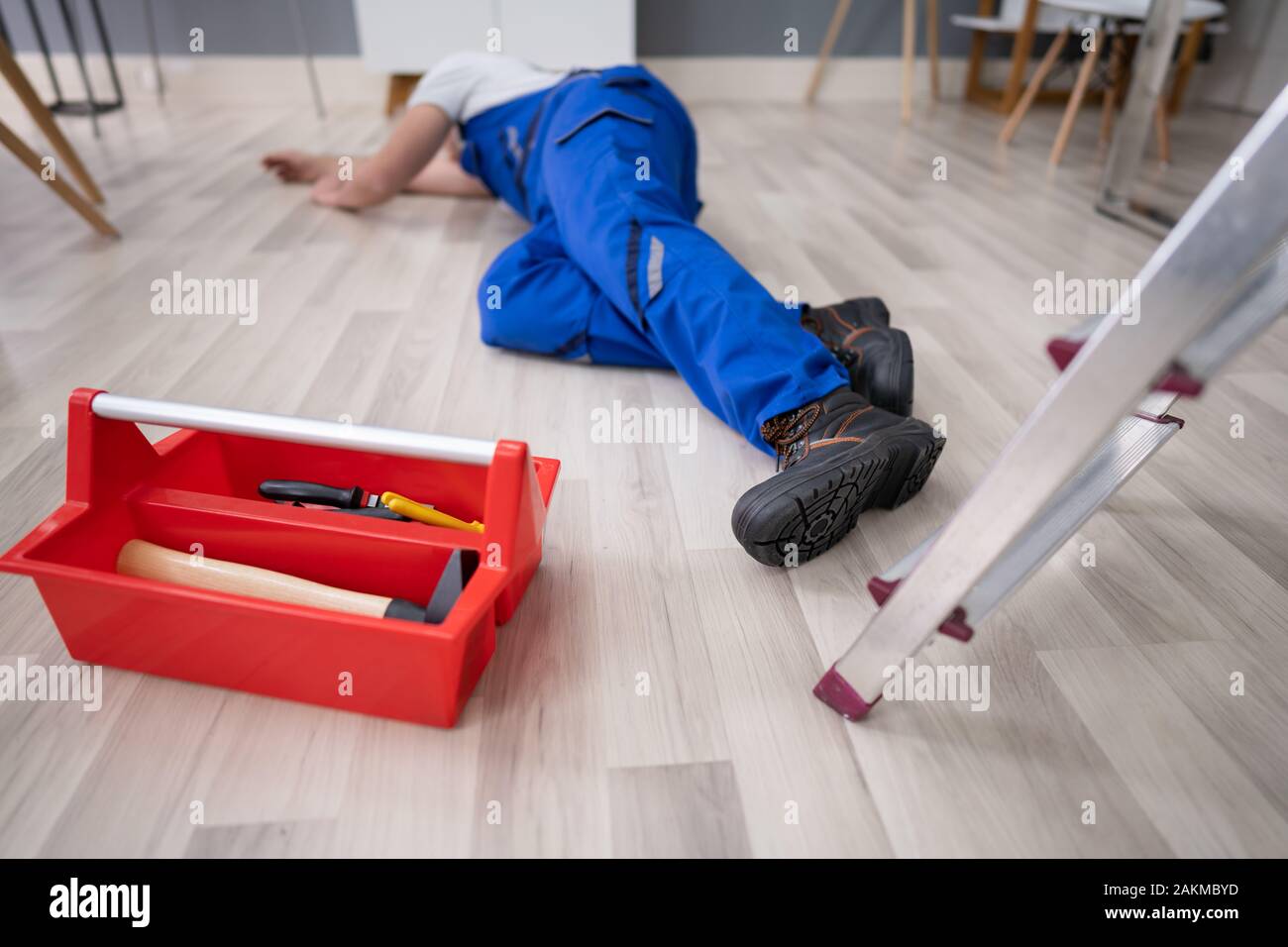 Unconscious Handyman Fallen From Ladder With Equipment Lying On Floor Stock Photo