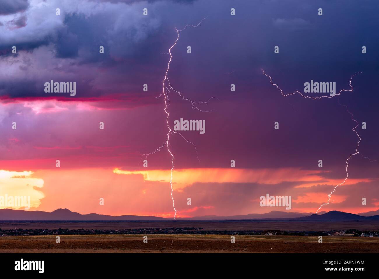 Lightning bolt strike from a monsoon thunderstorm as dramatic storm clouds take on sunset colors over Prescott Valley, Arizona, USA Stock Photo