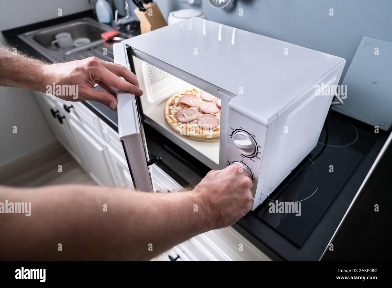 Human Hand Baking Pizza In Microwave Oven Stock Photo