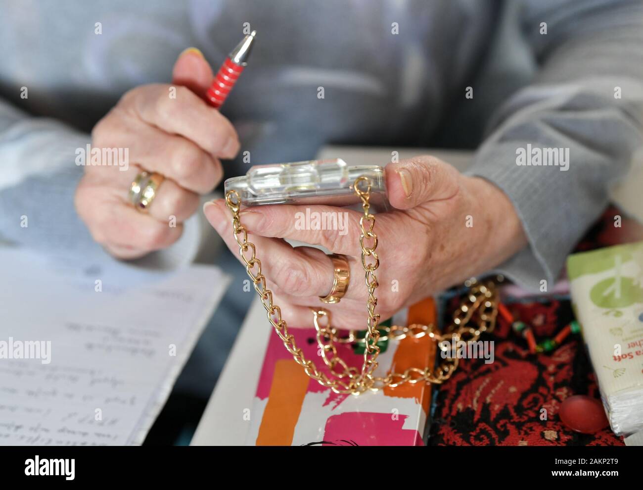 Berlin, Germany. 04th Dec, 2019. A senior citizen is holding her smartphone with a golden chain in her hands. She takes part in training courses for seniors on the topic of 'digital media' in the 'Versilberer-Cafe' of the association 'Wege aus der Einsamkeit e.V.'. Credit: Jens Kalaene/dpa-Zentralbild/ZB/dpa/Alamy Live News Stock Photo