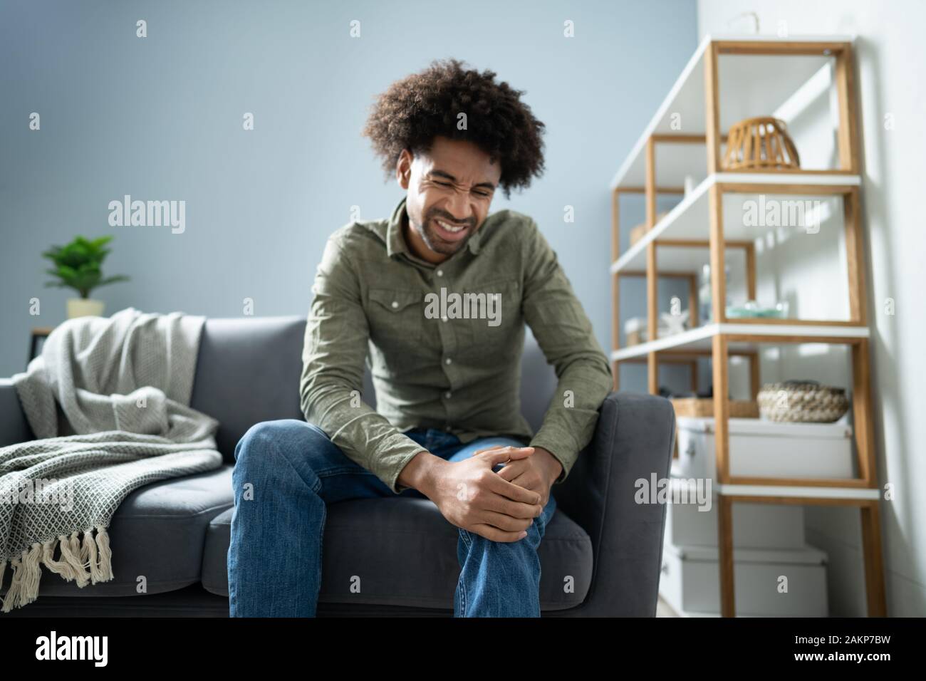 Man Suffering From Knee Pain Sitting On Sofa Stock Photo Alamy