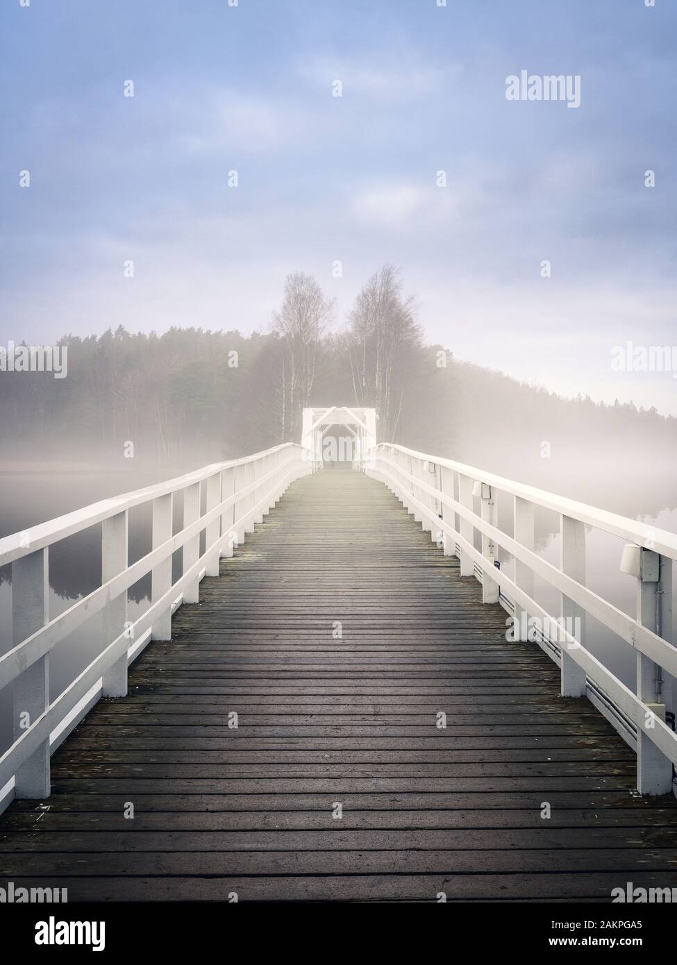 Old wooden bridge with mist haze mood and calm air at autumn morning in Finland Stock Photo