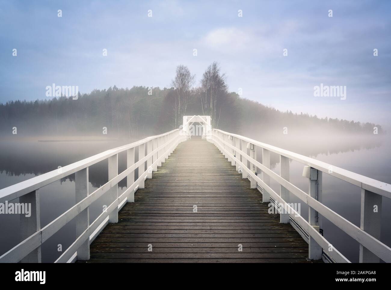 Old wooden bridge with mist haze mood and calm air at autumn morning in Finland Stock Photo