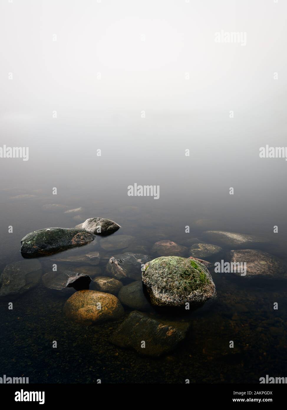 Calm and minimalist landscape with beach stones and foggy horizon at autumn morning in Finland Stock Photo