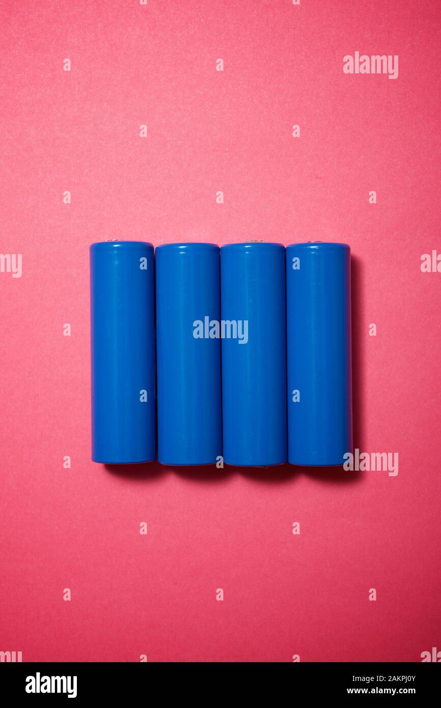Four small batteries on a pink table. Stock Photo