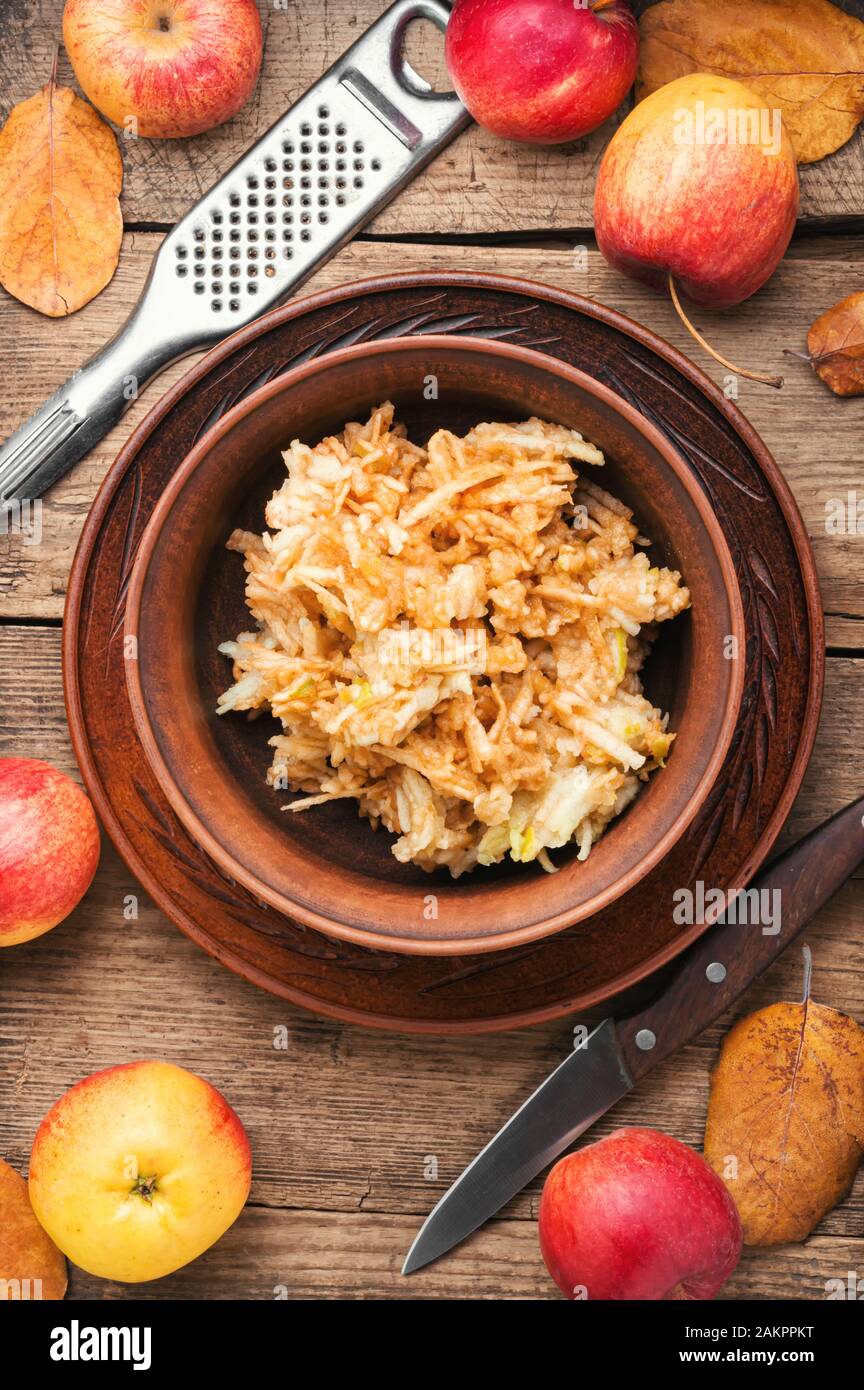 Grated ripe autumn apples in a plate on a wooden old table Stock Photo
