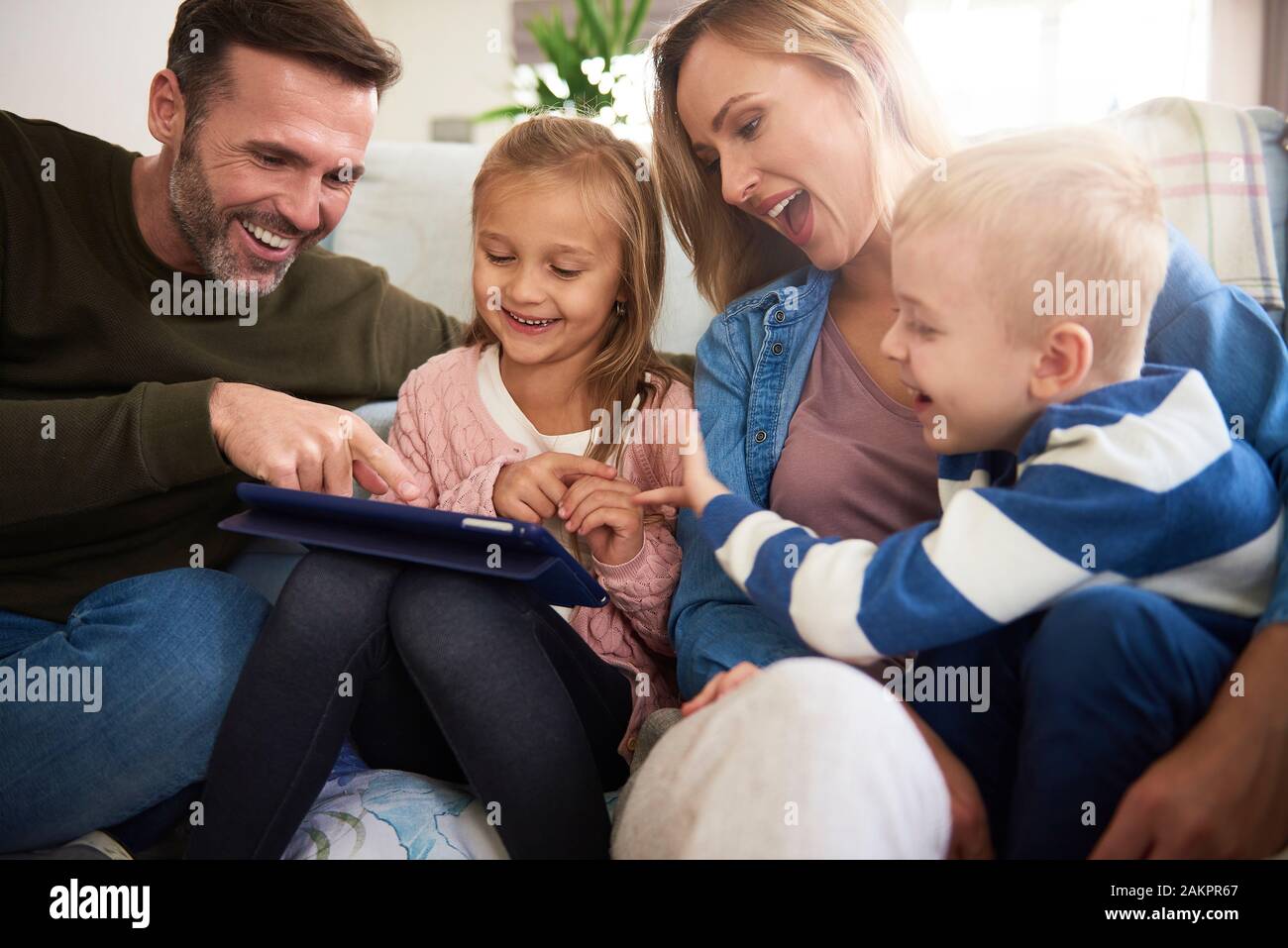 Family with tablet spending time together in living room Stock Photo