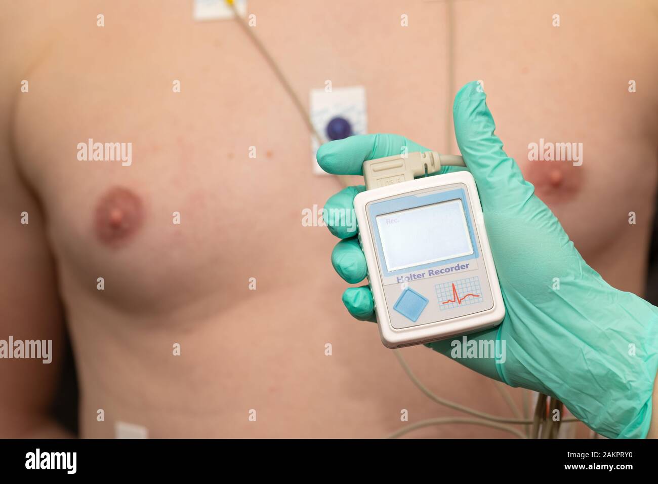 Doctor's hand applying holter heart monitor on young man's chest Stock Photo