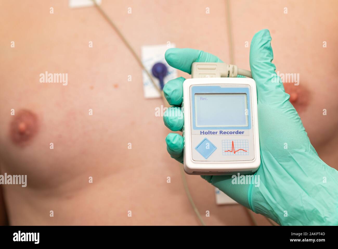 Doctor's hand applying holter heart monitor on young man's chest Stock Photo