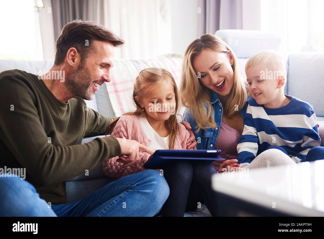 Happy family with tablet spending time together in living room Stock Photo