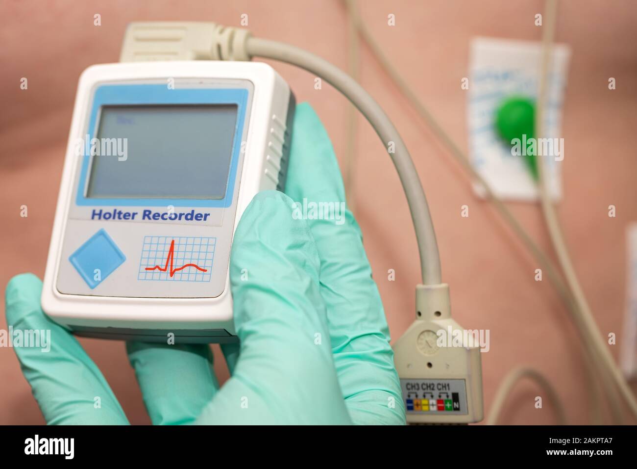 Doctor's hand applying holter heart monitor on young man's chest Stock Photo