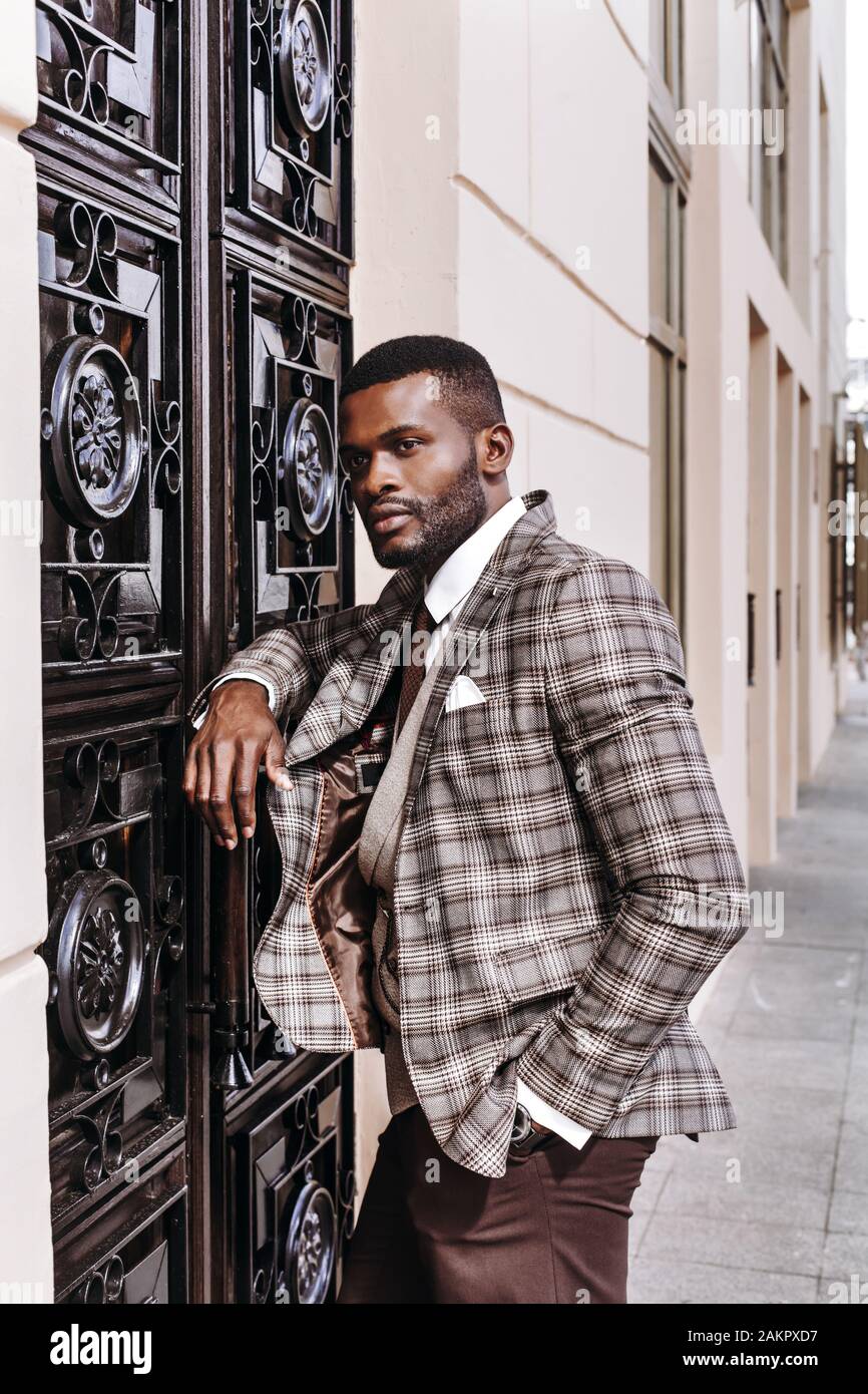 leaning on the decorated wall, entrance door, stylish luxury expensive business look, well dressed gentleman, urban men, city life, high fashion look Stock Photo
