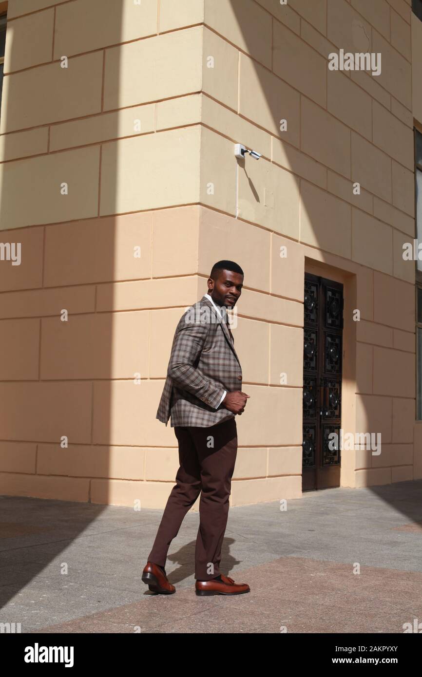 african american male fashion model walking towards the camera, wearing brown suit. stylish luxury expensive business look, well dressed gentleman Stock Photo