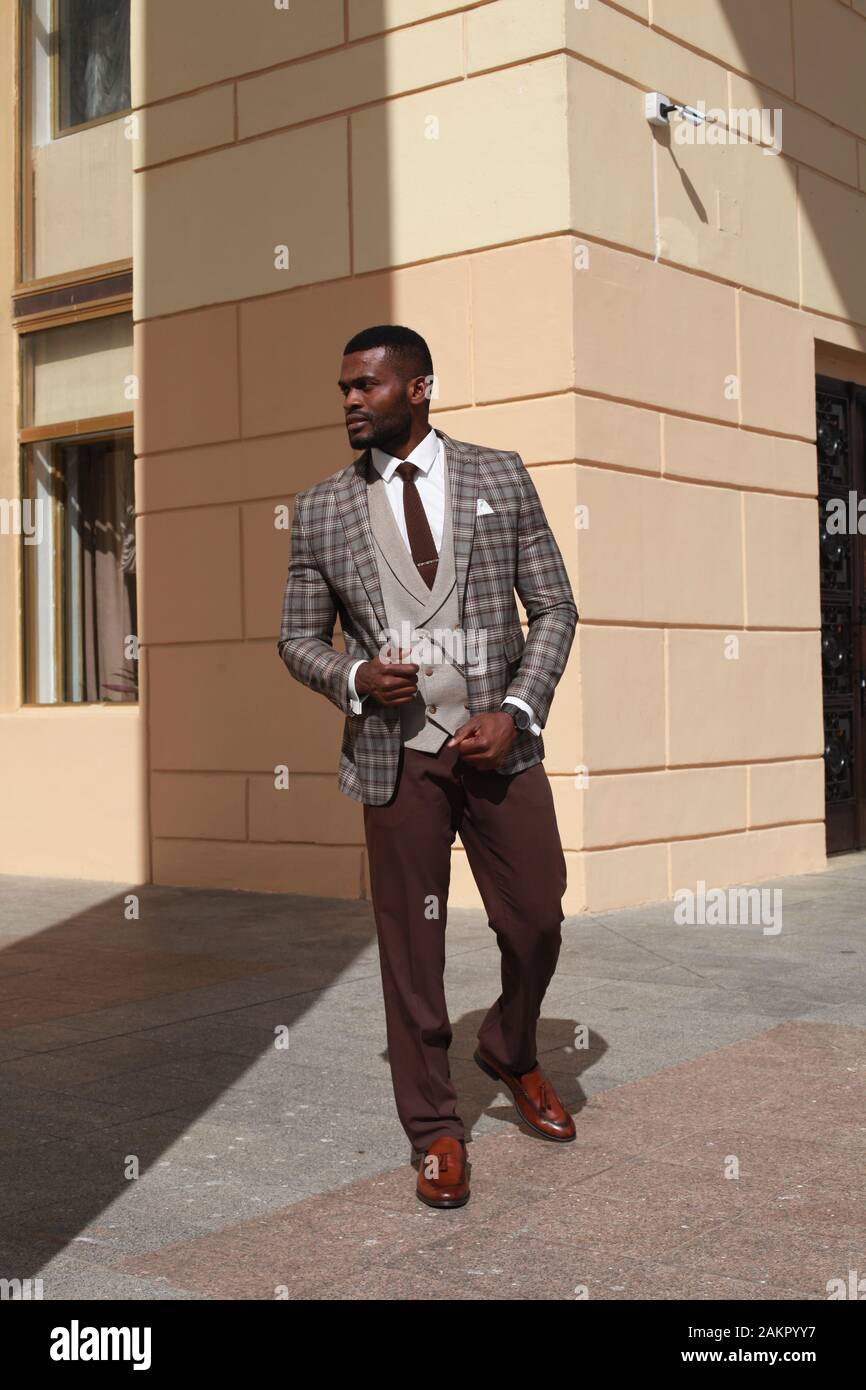 african american male fashion model walking towards the camera, wearing brown suit. stylish luxury expensive business look, well dressed gentleman Stock Photo