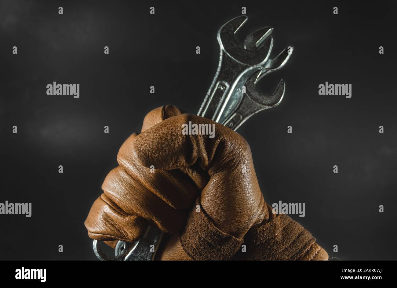 wrenchs were holding by leather glove man hand in dark light Stock Photo