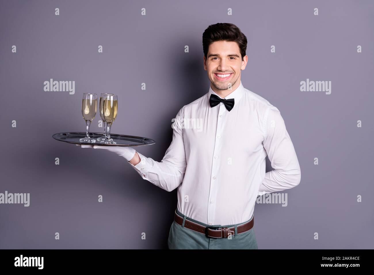 Portrait of positive cheerful restaurant staff worker waiter hold tray with alcohol give order