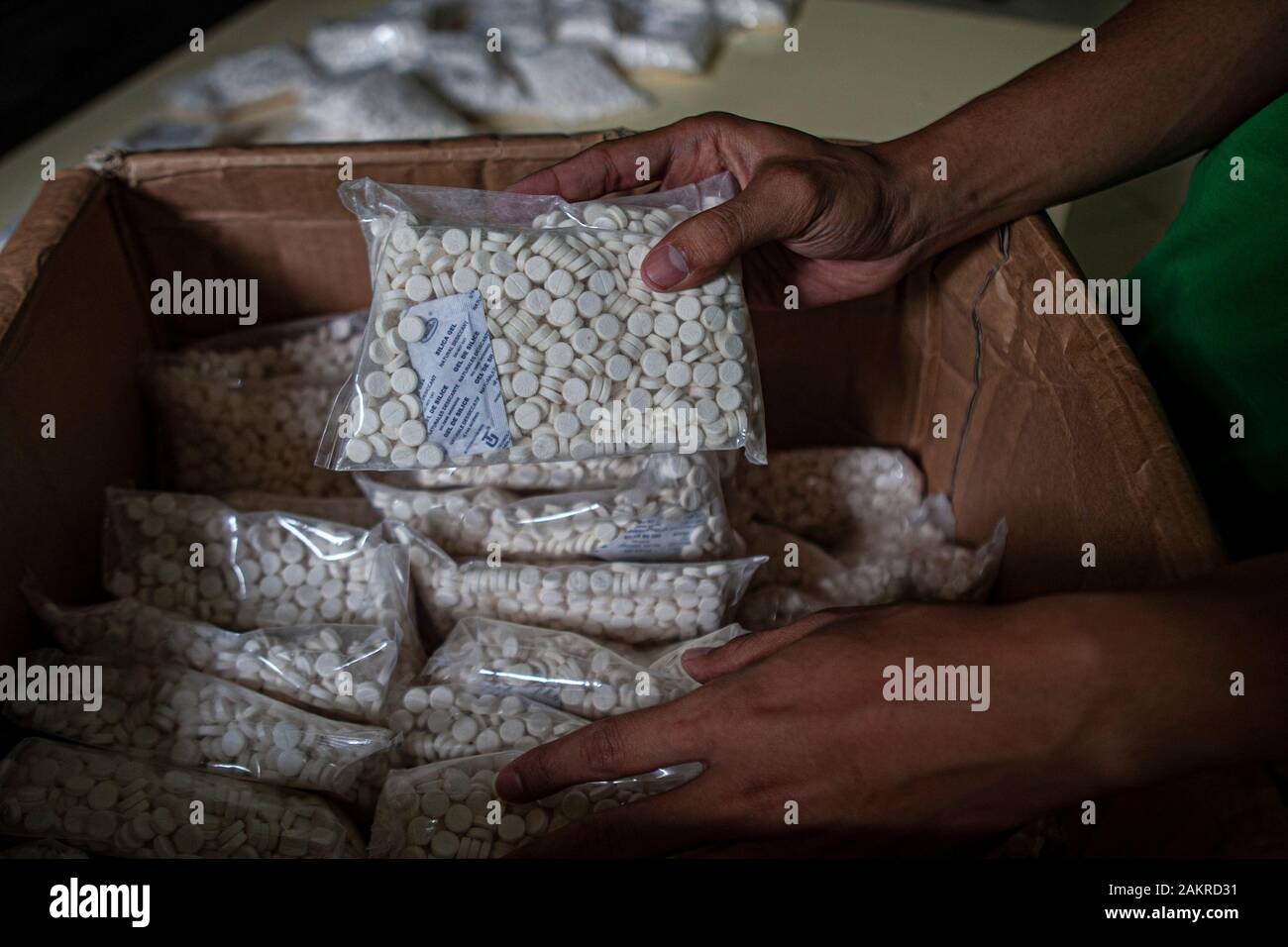 Hands of an officer put illegal drugs in a box at the BPOM Office in Palu city.The Palu City Food and Drug Supervisory Agency (BPOM) secures 400,000 drugs without a marketing authorisation from a seller. This drug if consumed in excessive amounts can cause illness to death because it has a high dose. Stock Photo