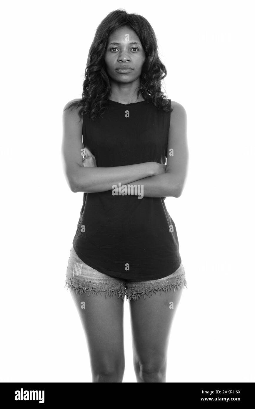 Studio shot of young black African woman standing with arms crossed ...