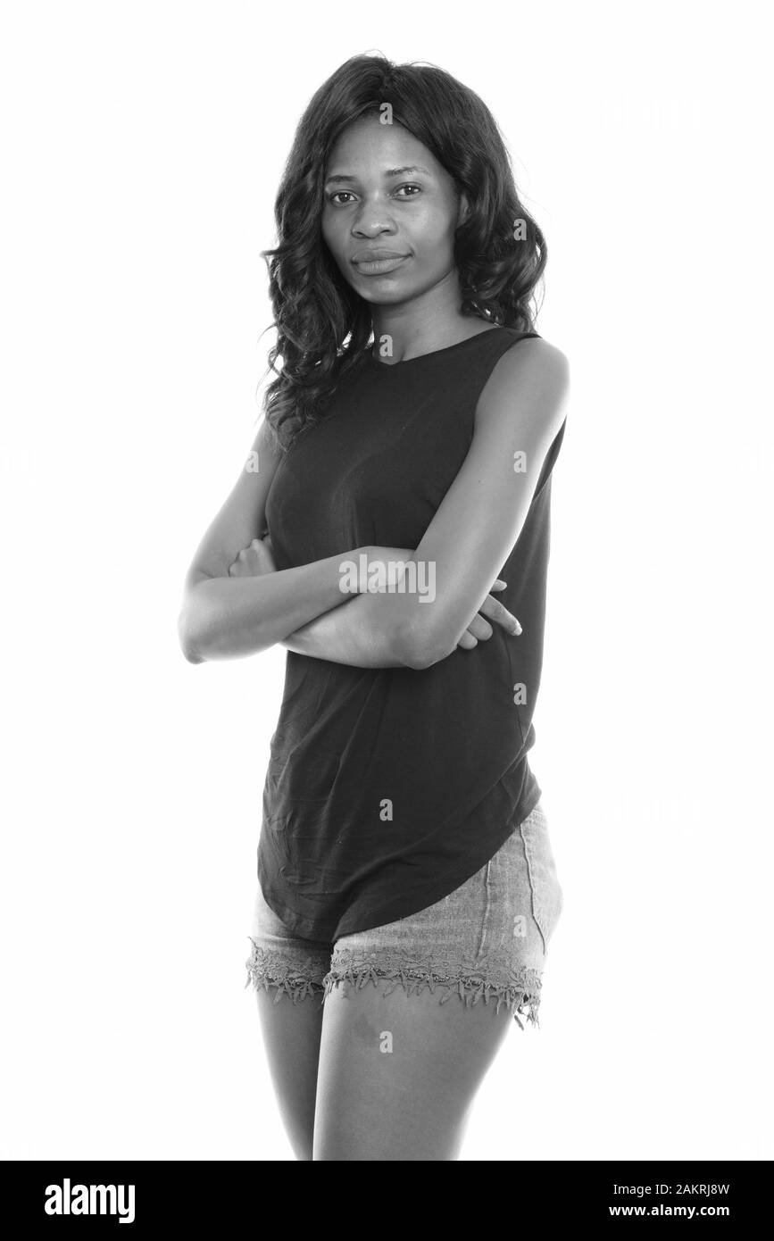 Studio shot of young black African woman standing with arms crossed ...