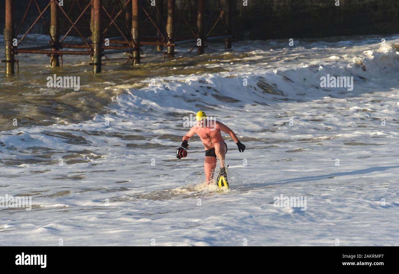 Brighton UK 10th January 2020 - A member of Brighton Swimming Club enjoys a chilly dip in the sea on a sunny morning by Brighton Palace Pier but wet and windy weather is forecast to return across the country over the next few days  . Credit: Simon Dack / Alamy Live News Stock Photo