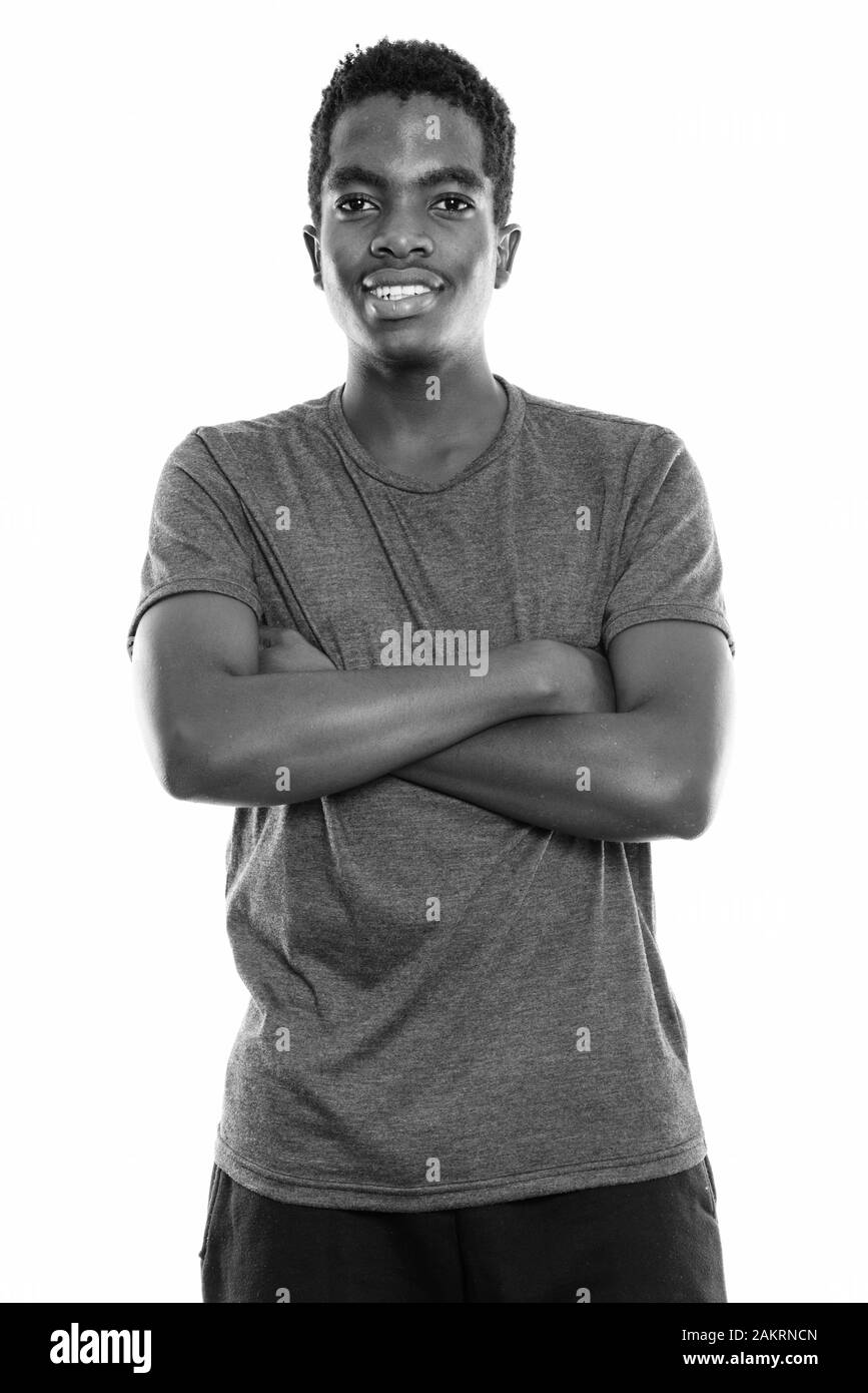 Studio shot of young happy black African teenage boy smiling with arms ...