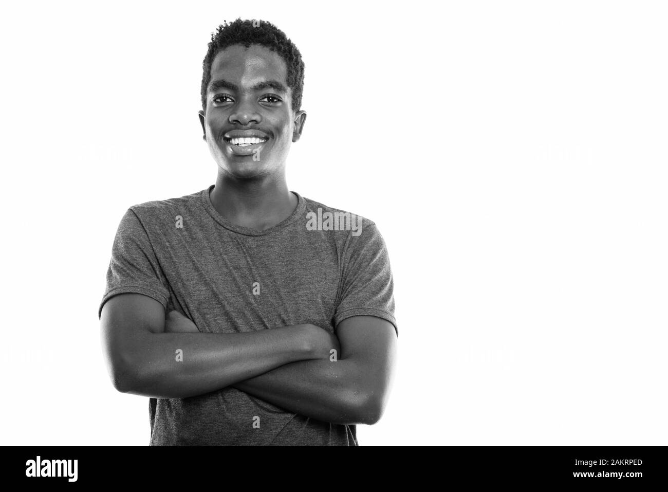 Studio shot of young happy black African teenage boy smiling with arms ...