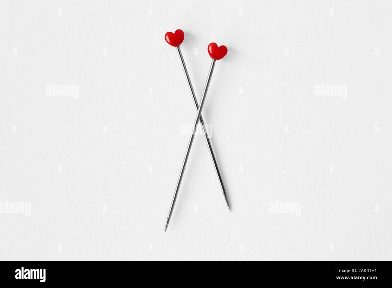 Two heart shaped pins on white background - Concept of love and relationship Stock Photo