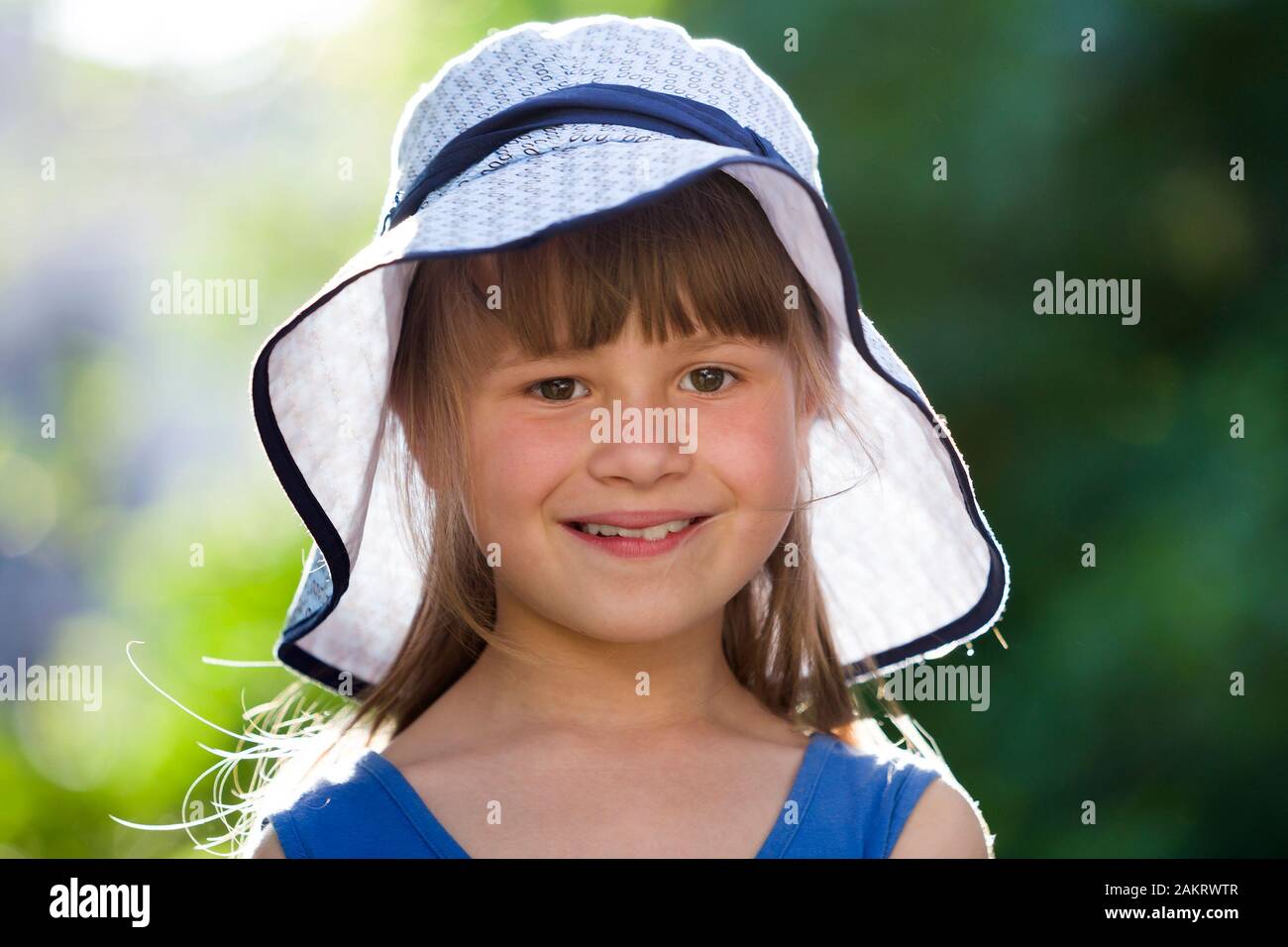 Close-up portrait of happy smiling little girl in a big hat. Child ...