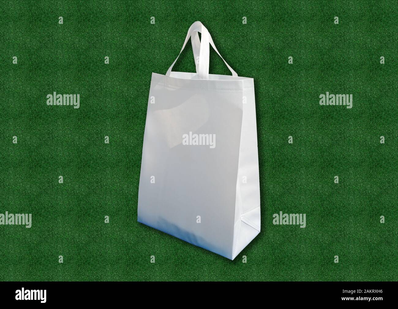 White fabric cloth Recyclable ECO Bag on Green Grass background. Replacement plastic bag. Save Earth ecology. Non Woven Bag Good for the Environment. Stock Photo