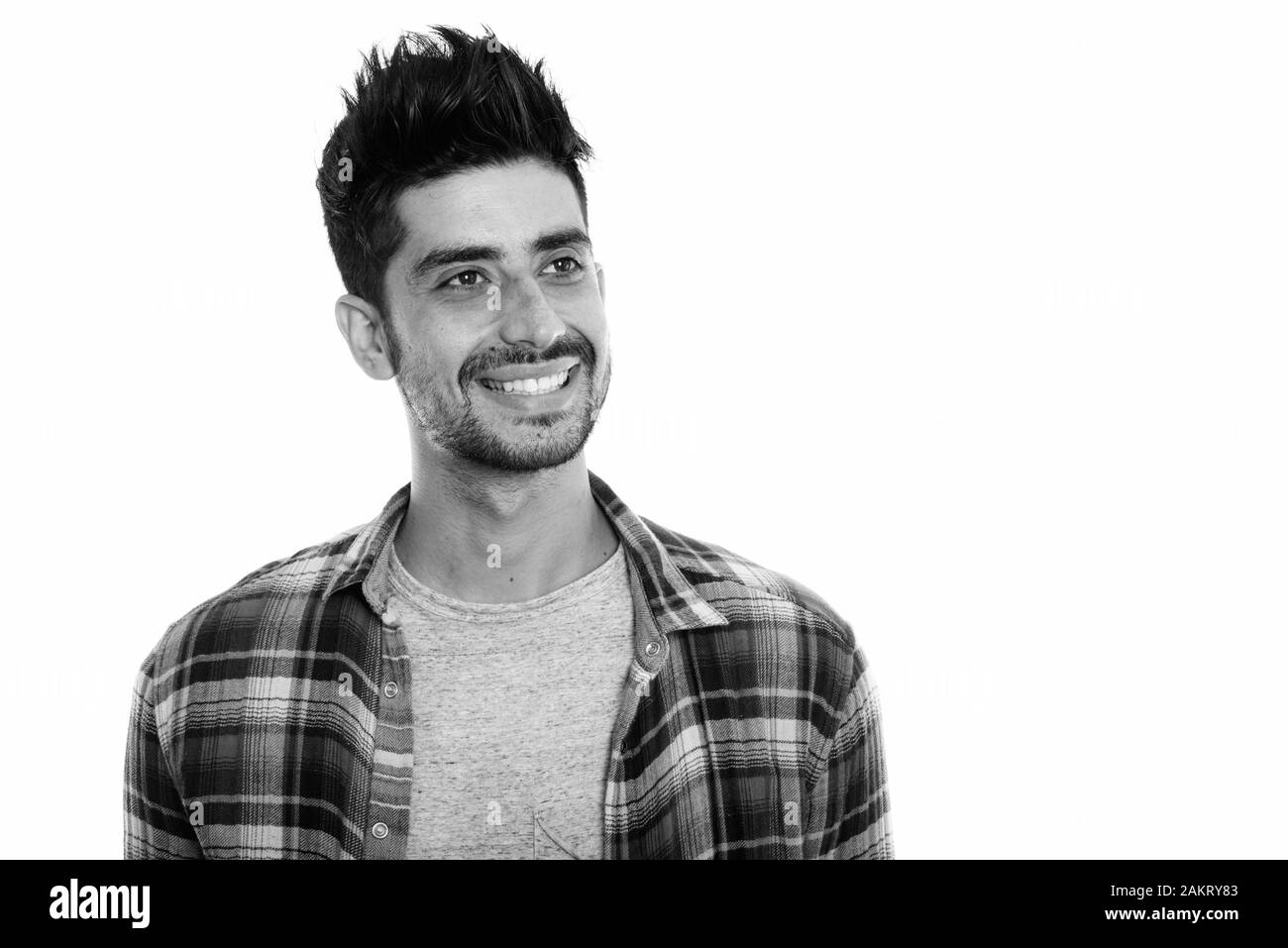 Studio shot of young happy Persian man smiling and thinking while ...