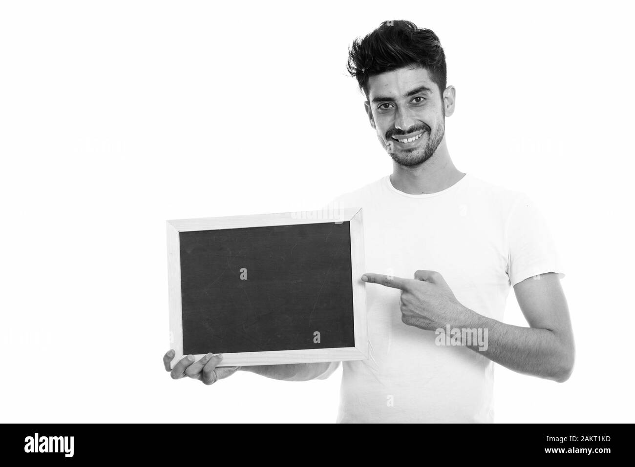 Studio shot of young happy Persian man smiling while holding and ...