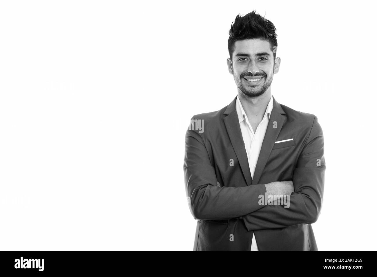Studio shot of young happy Persian businessman smiling with arms ...