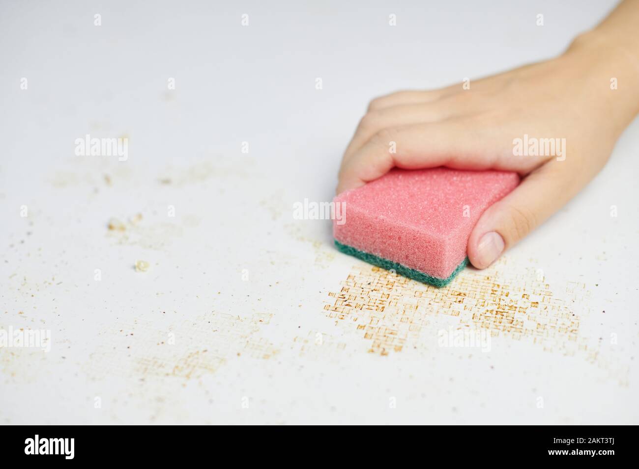 Sponge in woman hand removes dirt, bread crumbs and leftovers. Cleaning kitchen table. Household chores Stock Photo