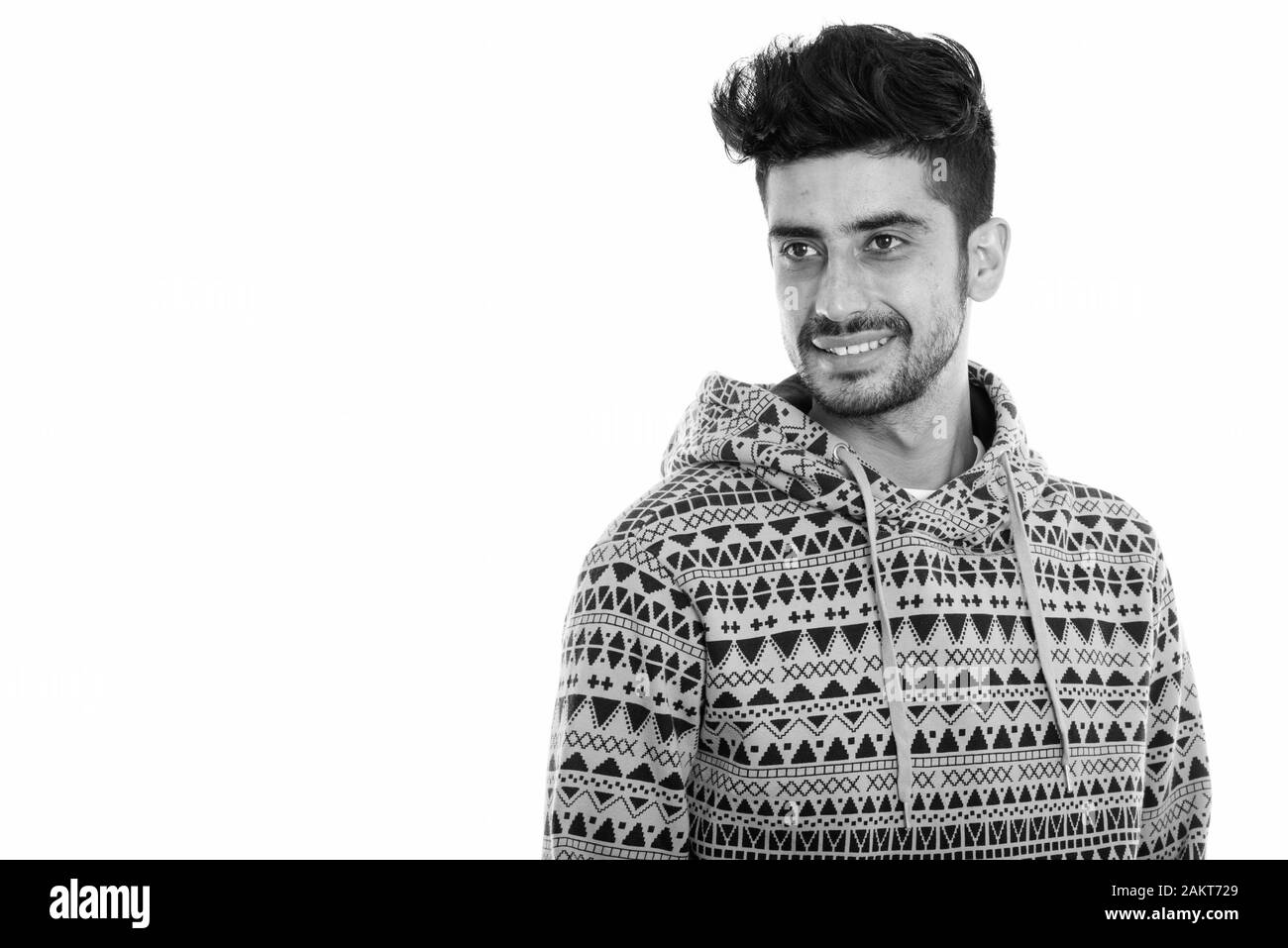 Studio shot of young happy Persian man smiling while thinking and ...