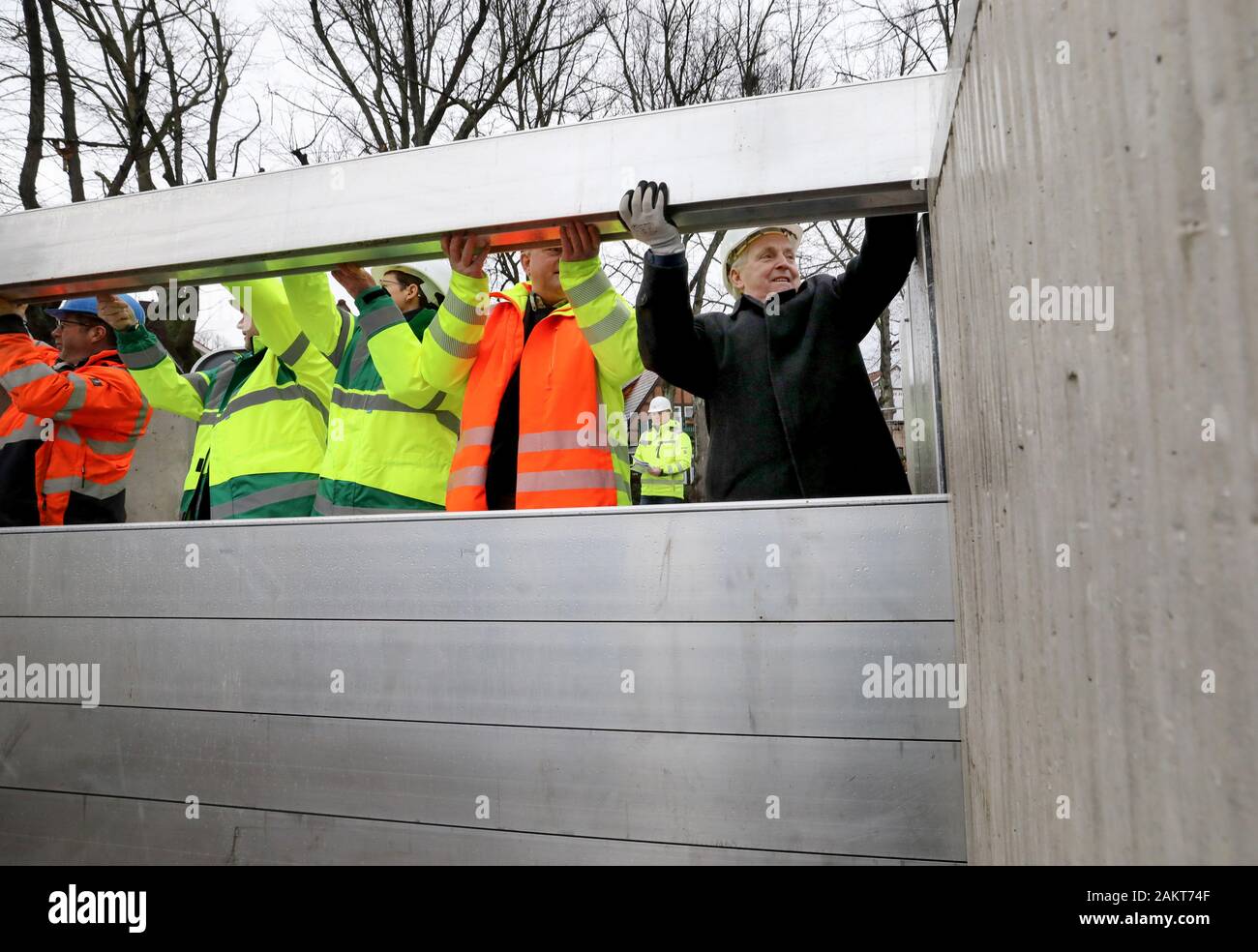 10 January 2020, Mecklenburg-Western Pomerania, Warnemünde: Till Backhaus (SPD, r), Minister of the Environment, helps to build a dam beam closure after the handover of the new storm surge protection wall at the southern Alter Strom, which can be used to close off passages in the wall if necessary. The structure, which is around 500 metres long, is 2.75 metres high and can therefore withstand water levels of up to 2.50. Due to the modular construction it is possible to raise the wall. Photo: Bernd Wüstneck/dpa-Zentralbild/dpa Stock Photo