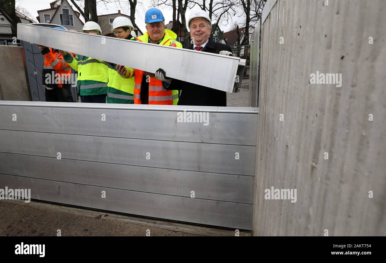 10 January 2020, Mecklenburg-Western Pomerania, Warnemünde: Till Backhaus (SPD, r), Minister of the Environment, helps to build a dam beam closure after the handover of the new storm surge protection wall at the southern Alter Strom, which can be used to close off passages in the wall if necessary. The structure, which is around 500 metres long, is 2.75 metres high and can therefore withstand water levels of up to 2.50. Due to the modular construction it is possible to raise the wall. Photo: Bernd Wüstneck/dpa-Zentralbild/dpa Stock Photo
