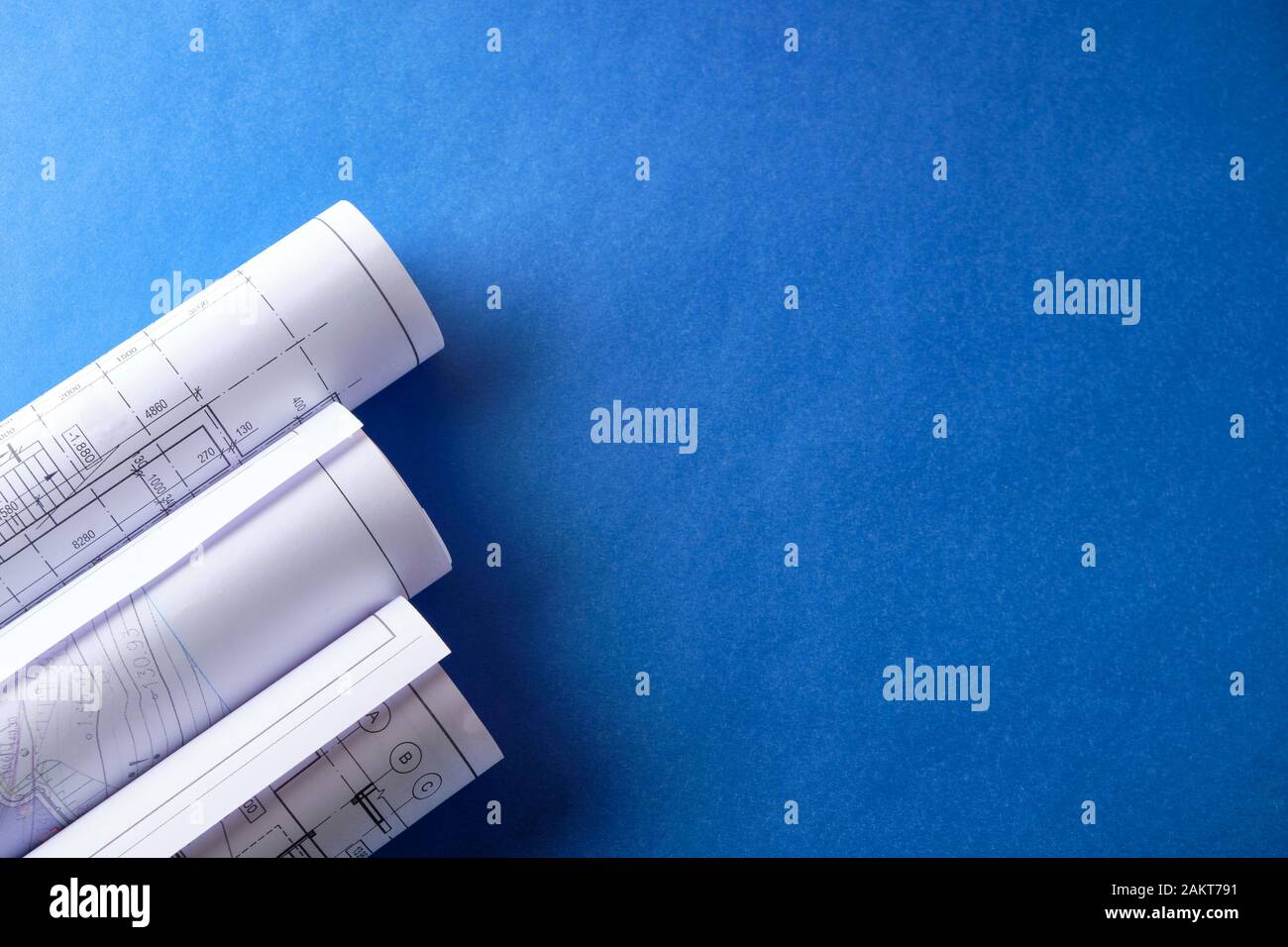 Rolled engineering drawings at blue background with copy space. Stock Photo