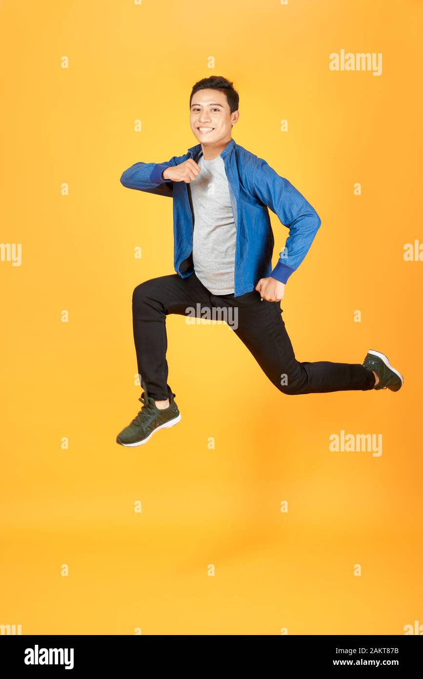 Young happy Asian teen jumping welcomely isolated on orange studio background Stock Photo