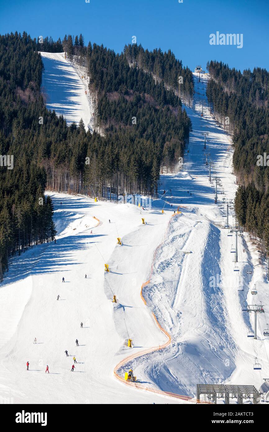 View of a ski resort area with skiers going down the slope Stock Photo