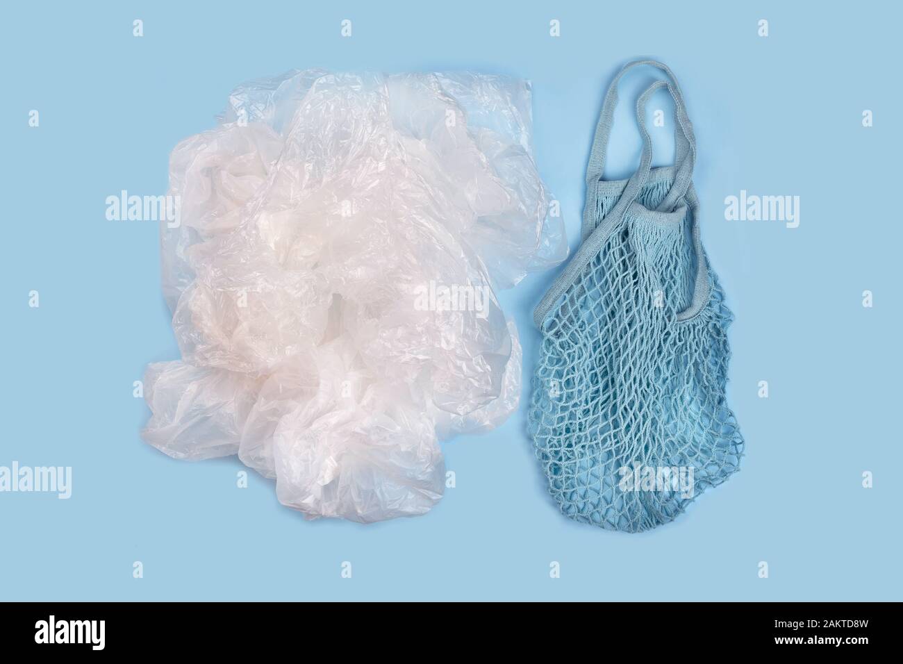 String reusable bags and a pile of plastic bags on blue background