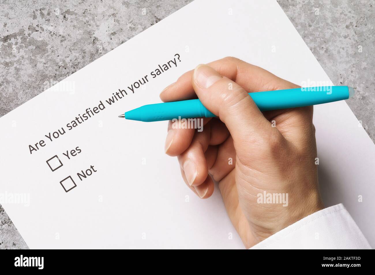 Hand with pen on a sheet of paper. The concept of an anonymous survey on estimated wages Stock Photo
